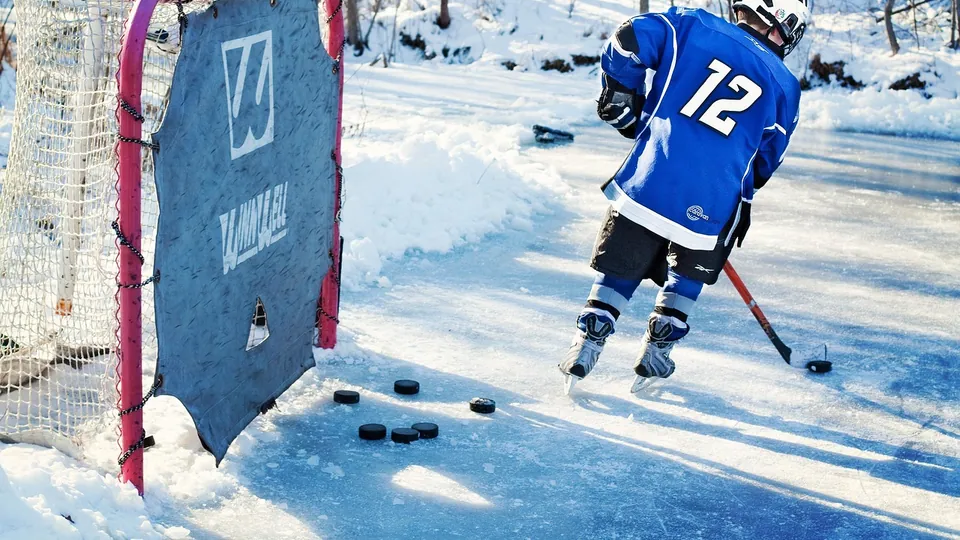 A hockey player with pucks on outdoor ice